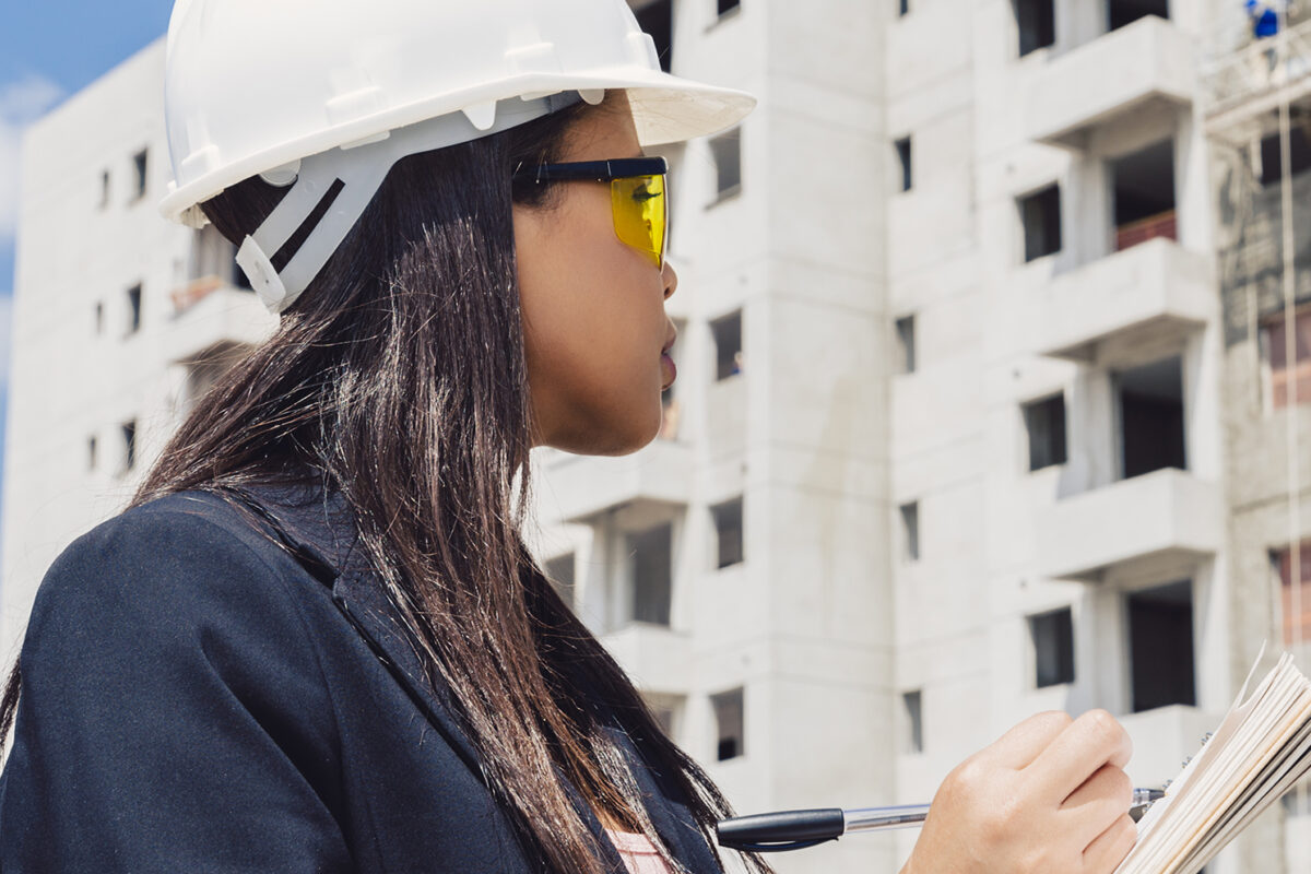 african-american-lady-safety-helmet-writing-notepad-near-building-construction3