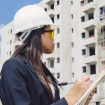 african-american-lady-safety-helmet-writing-notepad-near-building-construction3